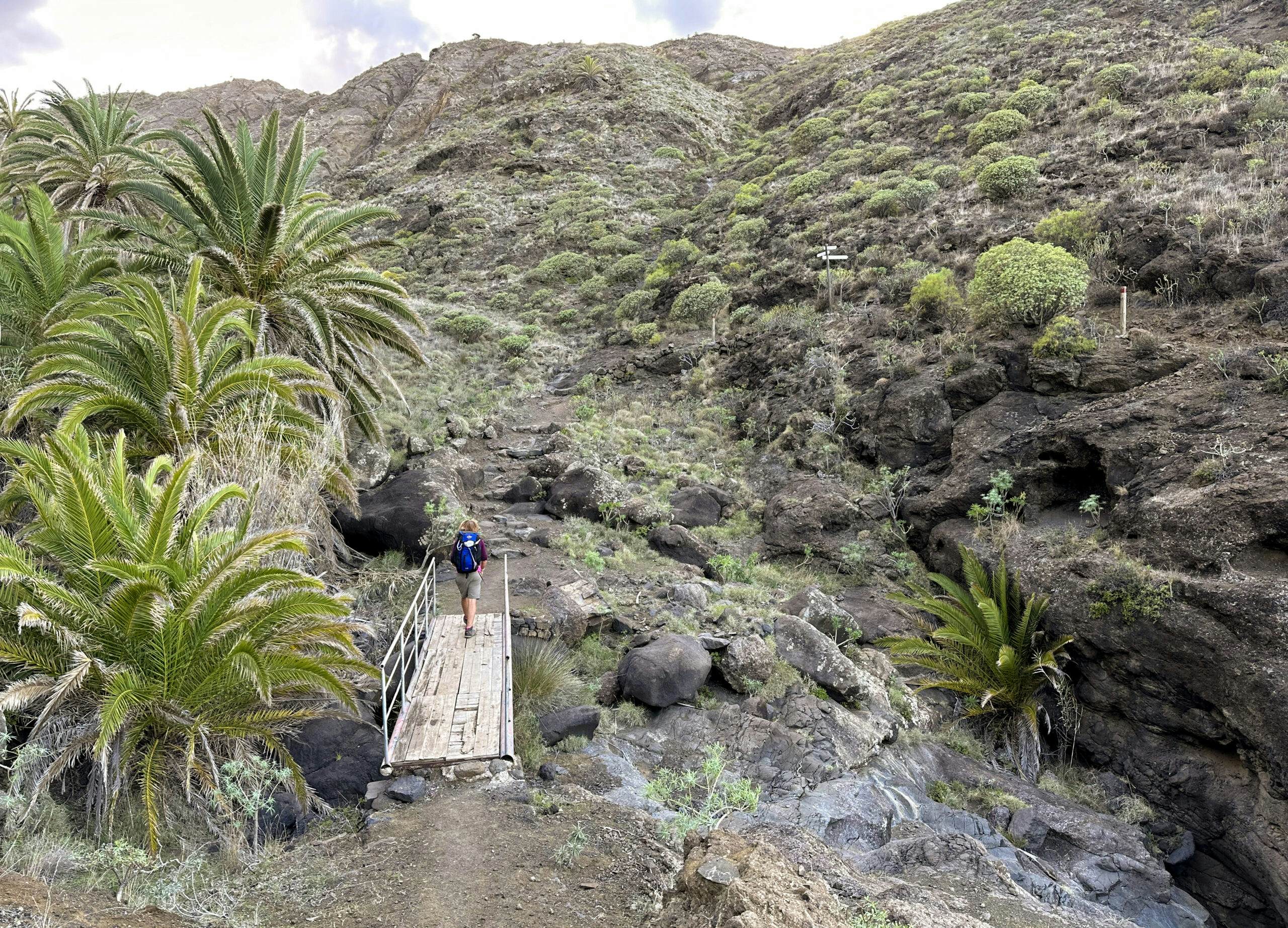 Wanderin auf dem Fernwanderweg GR-132 auf einer Brücke an der Küste vor La Caleta